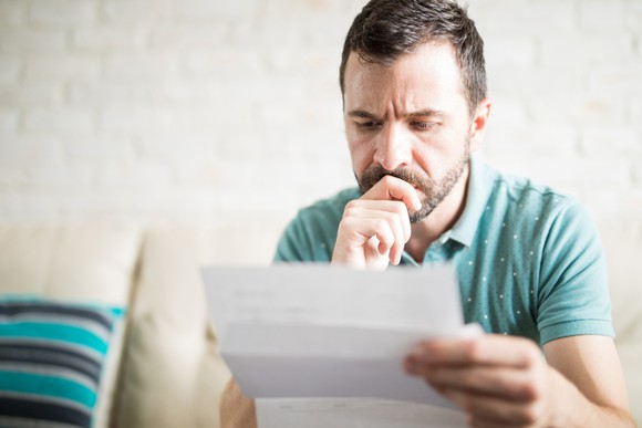 Man with serious expression resting hand on chin while looking at document