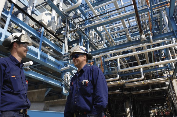 Two men in hard hats talking at an energy processing plant