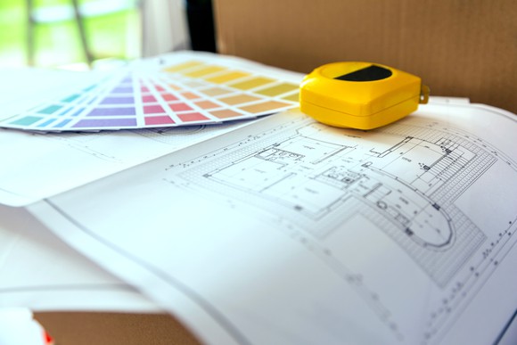Architectural plans, color samples, and a tape measure on a table