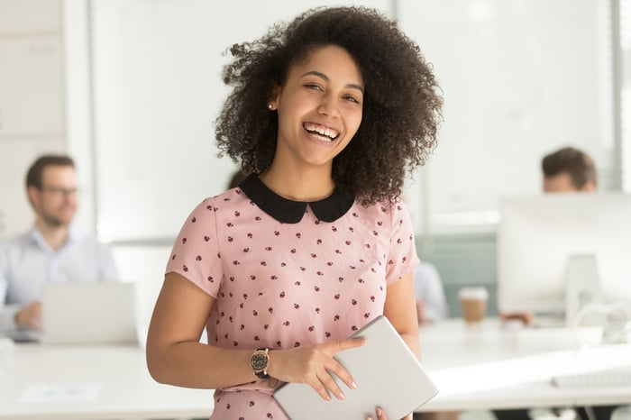 Smiling woman holding tablet.