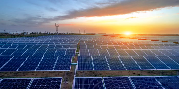A solar energy facility with the sun setting in the background.