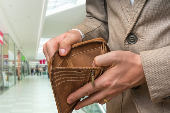 Man holding open wallet to reveal that it's empty