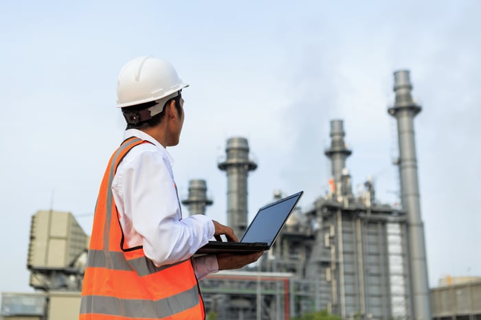 An engineer inspecting a gas turbine outside of a power plant.