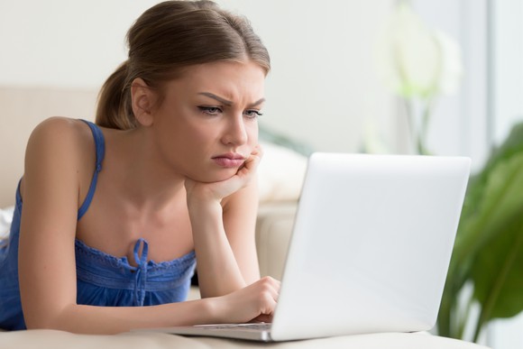 Confused looking woman sitting in front of laptop.