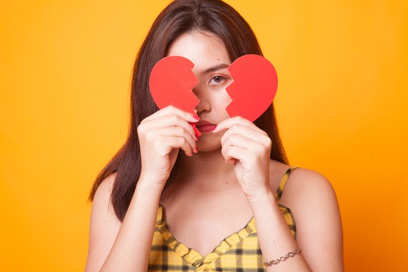 Woman holding up two halves of a heart