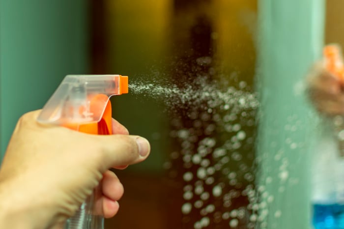 A cleaning product being sprayed onto a glass surface.