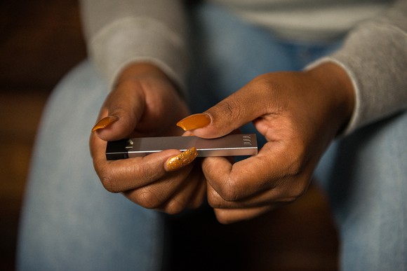 Close-up of a person's hands clutching a Juul device.