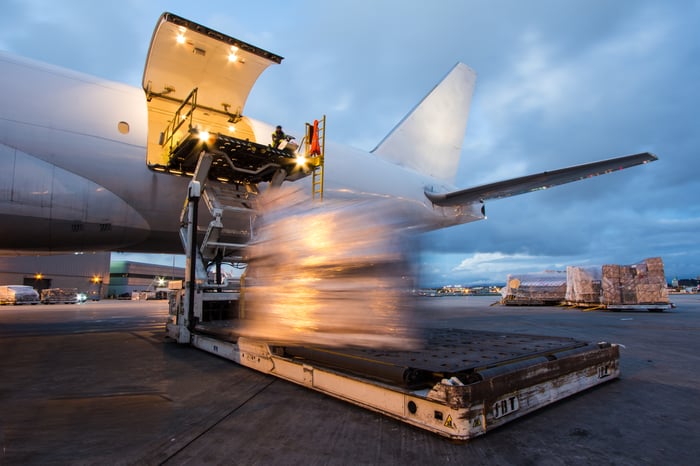 Cargo is unloaded from the back of an airplane.