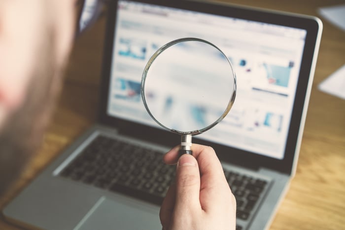 Magnifying glass held over laptop