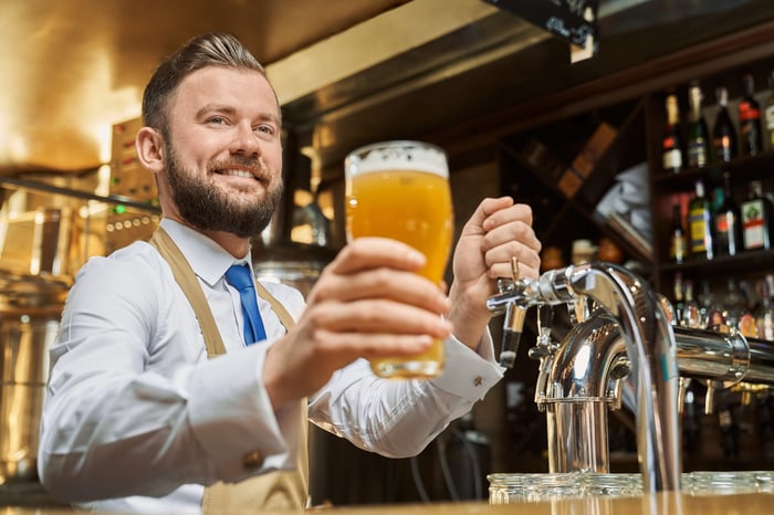 Man behind bar holding glass of beer