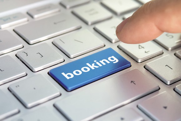 Person clicking on blue booking button on computer.
