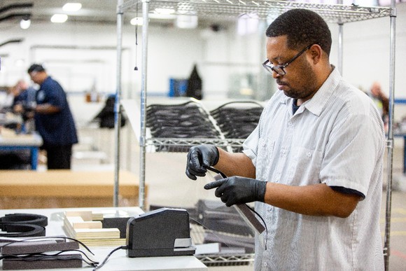 Workers on a factory floor assembling the protective shields.