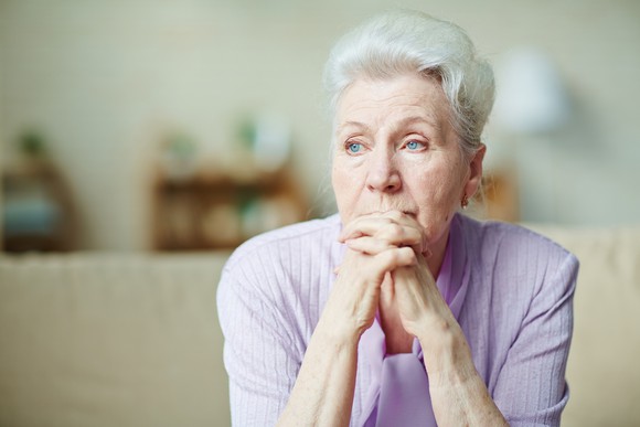 Senior woman looking worried with her hands clasped in front of her face