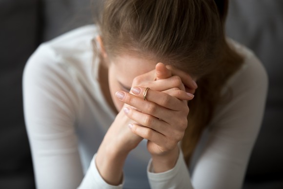 A woman holds her hands in front of her face.