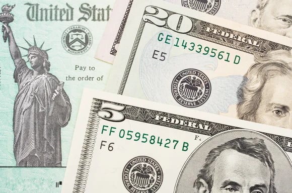 A check from the U.S. Treasury, with U.S. currency on top of it