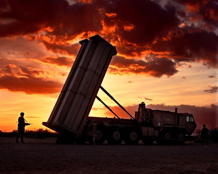 A THAAD unit aims toward the sky as the sun sets behind it.