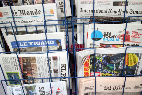 Various newspapers on display at a newsstand