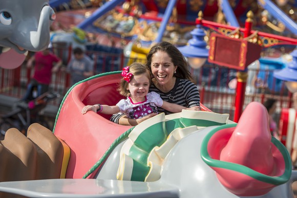 A woman with a child on a ride at Disney World.