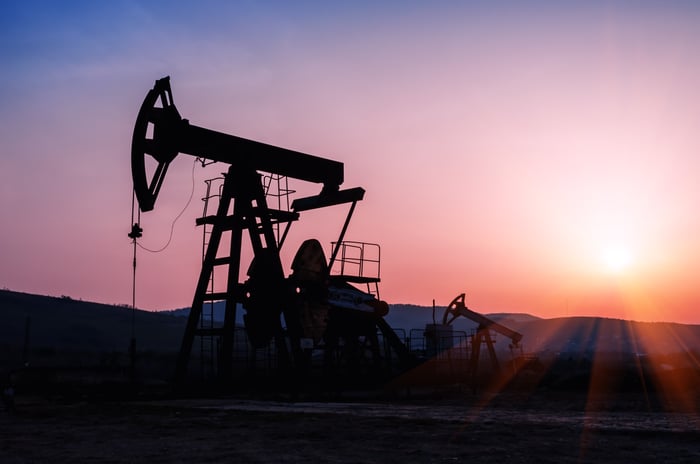 An oil pump silhouette with a red sunset in the background.