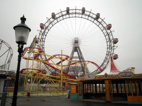 Photo of a ferris wheel and roller coaster in an abandoned theme park.