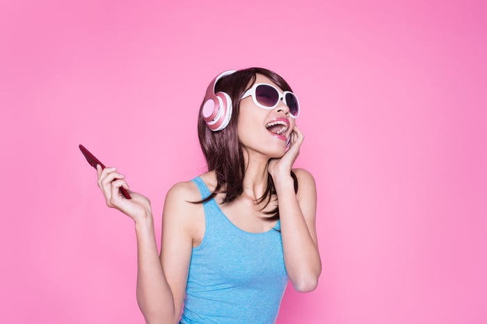 A woman wearing headphones and holding a smartphone