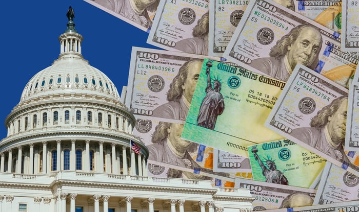 An image of the Capitol building in Washington, D.C., next to a messy pile of one hundred dollar bills and economic stimulus checks from the Treasury Department.