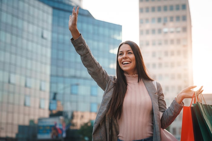 A young woman hails down a ride in a city.