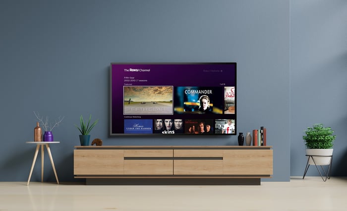 A wall-mounted television showing The Roku Channel home screen