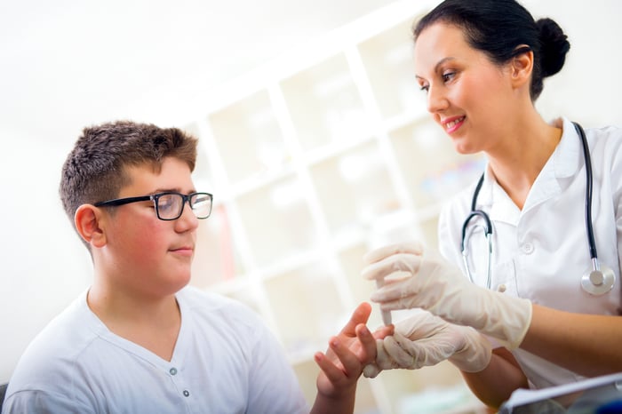 A nurse administering a finger prick to a diabetic patient.