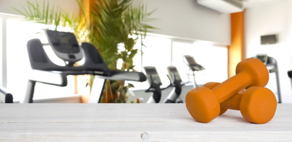 Two yellow dumbells with exercise machines in the background.