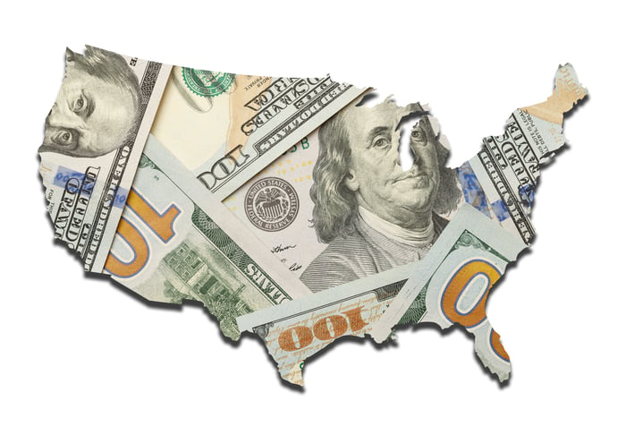 An outline of the United States that's been filled in by a pile of hundred-dollar bills.