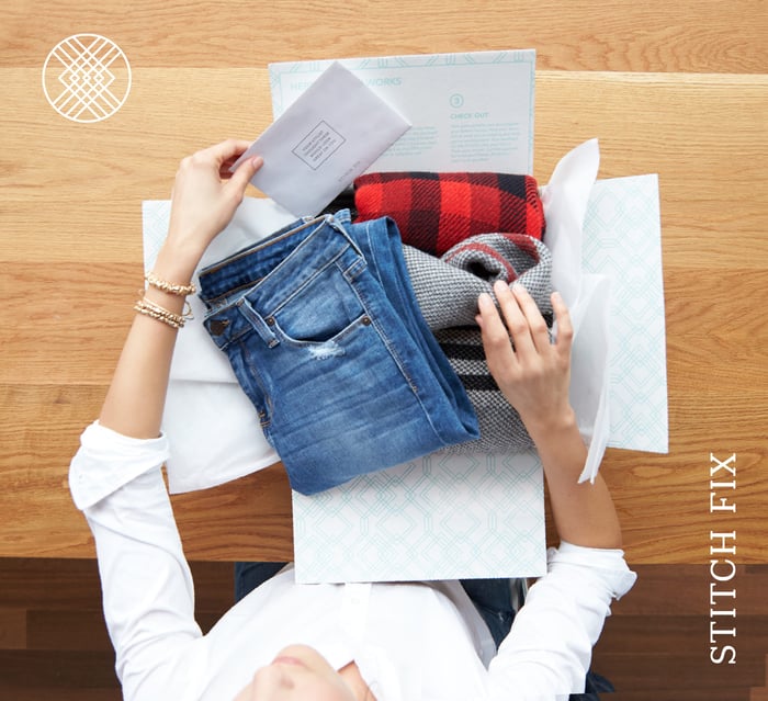 A woman unboxes a shipment from Stitch Fix.