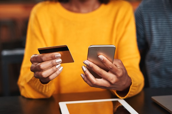 A woman holding a credit card and a mobile phone.