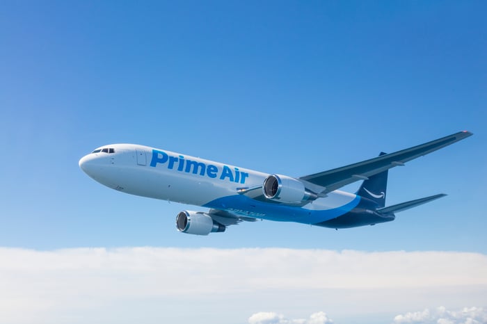An Amazon Prime Air plane flying through the air in front of a blue sky.
