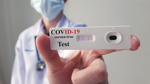 Doctor holding up COVID-19 test kit.
