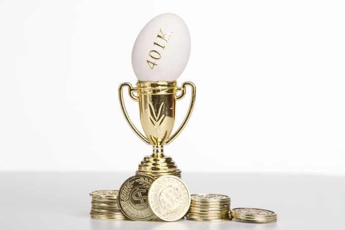 Egg with 401k written on it, sitting in the cup of a trophy, with golden coins scattered around the base.