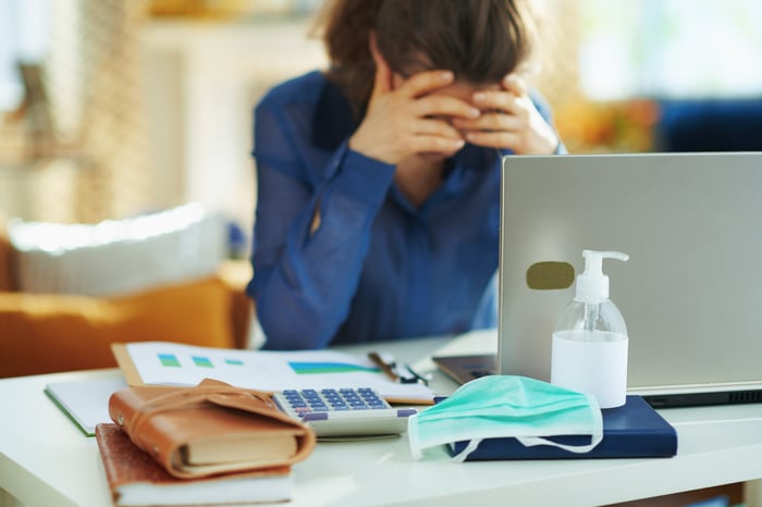 Woman at laptop covering her face