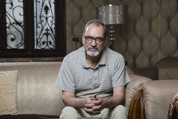Older man with serious expression seated on couch