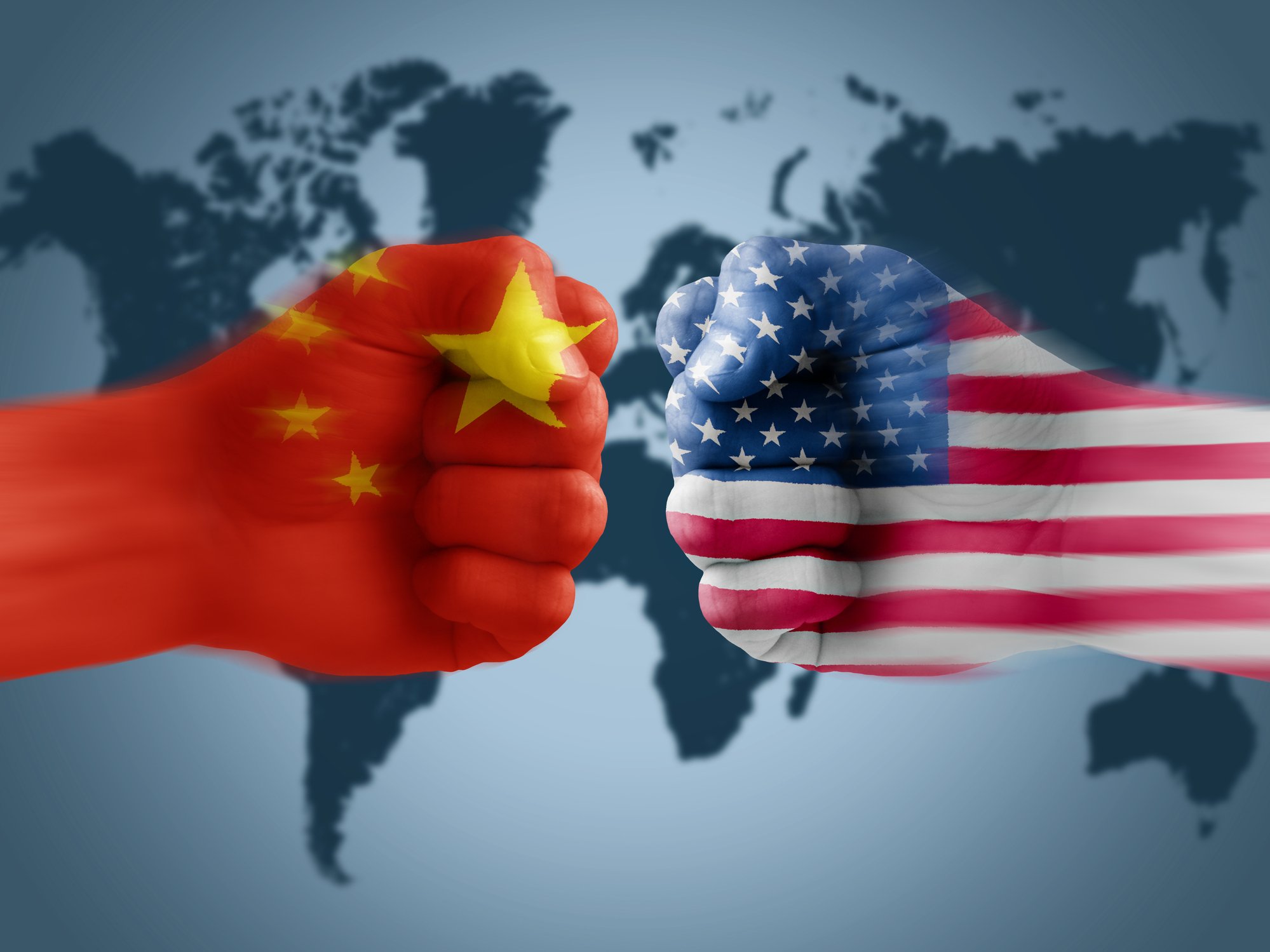 Two fists meet, one emblazoned with Chinese flag and one with U.S. flag