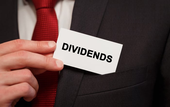 Man putting a card reading DIVIDENDS into his suit breast pocket.