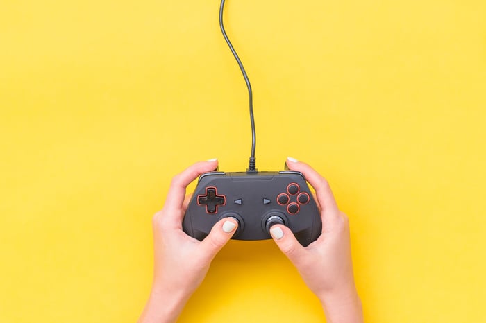 Two hands holding a video game controller with a yellow background