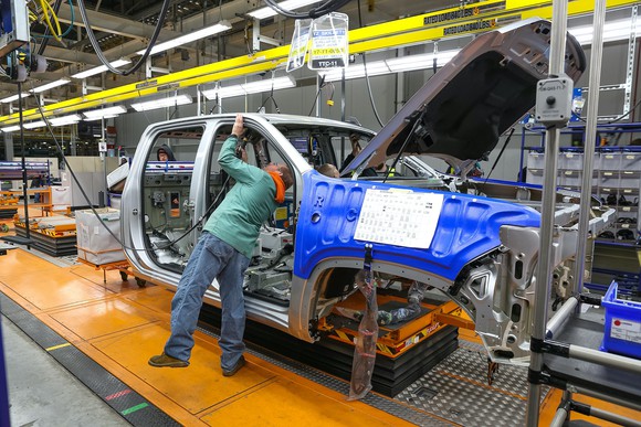 A worker at GM's factory in Fort Wayne, Indiana, attaches parts to a truck on the assembly line.