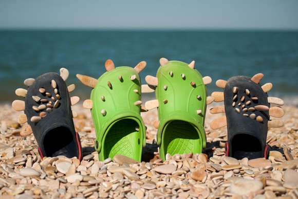 Foam clogs on the beach with the ocean in the background