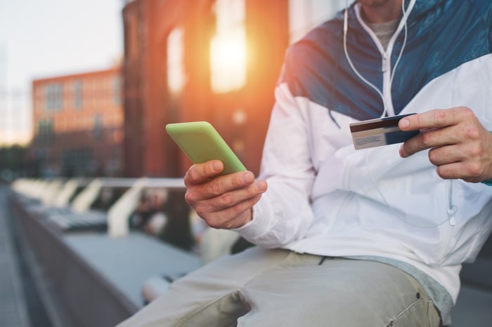 Man with credit card and mobile phone on a bench.