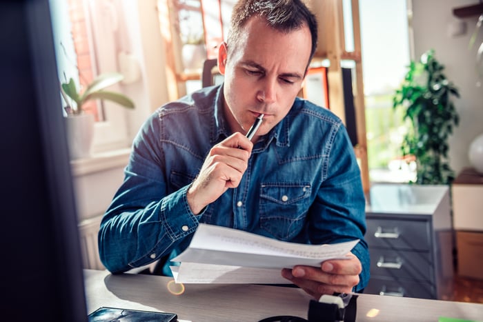 Man holding pen against mouth while reading document