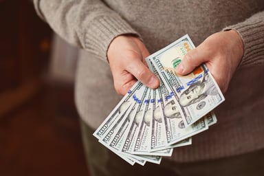 money man holding thousand dollars in hundred bills