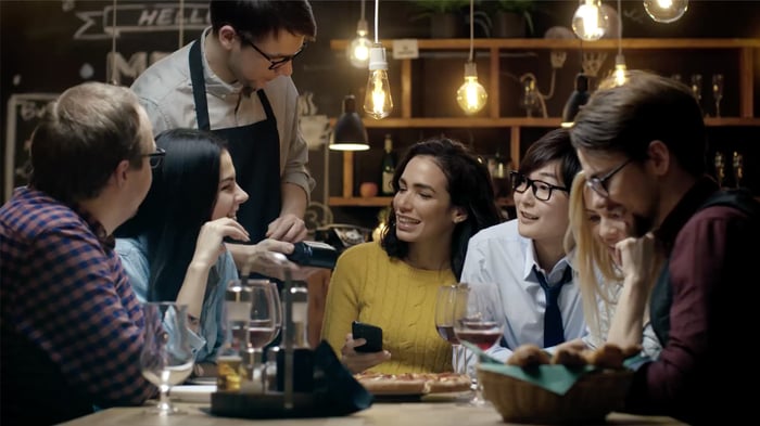Shift4 group of people paying for the goods at a restaurant or bar.