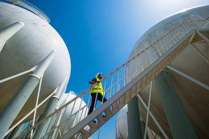 A man walking up a stairwell between multiple liquified petroleum gas storage tanks