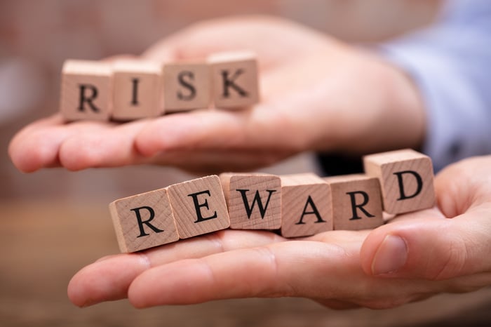 Two hands holding blocks spelling out the words "risk" and "reward"