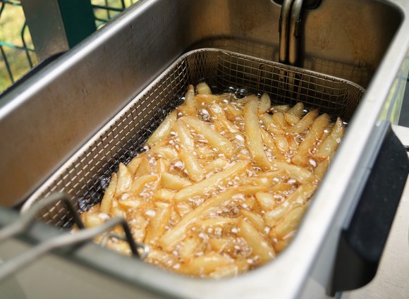 French fries cooking in an industrial deep fryer.